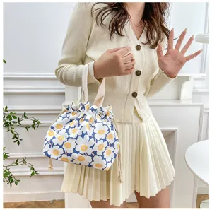 Detail shot of a cute floral canvas drawstring lunch bag, featuring portable handles and bento style.