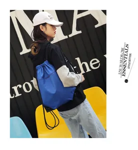 Detail view of the lightweight blue nylon drawstring backpack, showing front zipper pocket and cords.