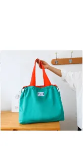 Grand sac de shopping pliable écologique avec corps vert et poignées orange pratiques.
