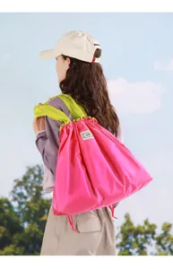 Grand sac à dos pliable rose avec cordon de serrage et lanière verte pour le shopping.