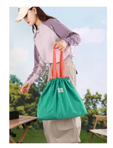 Sac cabas pliable vert en détail, grand sac de shopping avec anses rouges pour le voyage.