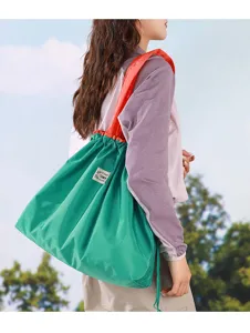 Vue détaillée du sac de shopping pliable avec corps vert, sangle orange et cordon coulissant.