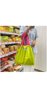 Sac de courses pliable et reutilisable avec corps vert vif et anses roses pour le quotidien.