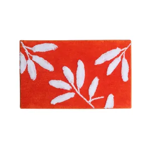 Tapis de bain tufté orange avec motif de feuilles blanches, absorbant et antidérapant.
