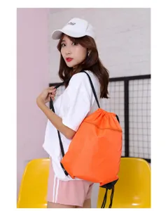 Orange drawstring backpack detail showing front zipper pocket and durable black cords on model.