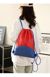 Detailed shot of a red and blue waterproof drawstring backpack worn by a model in a clean room.