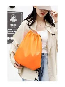 Detailed view of bright orange drawstring backpack being worn, showing cinch design and vibrant color.