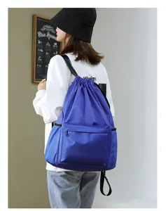 Blue drawstring backpack detail showing large capacity, front zip pocket, and comfortable straps.