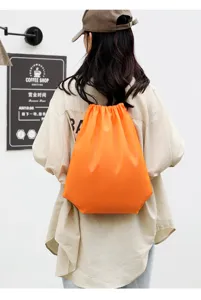 Orange drawstring backpack, polyester foldable sports gym bag, lightweight storage sack.