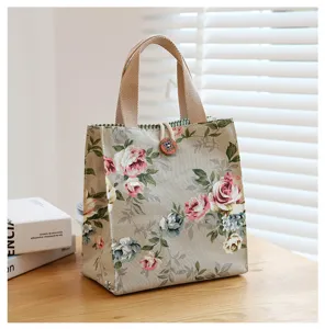 Detail shot of vintage floral canvas lunch bag on wooden table with elegant woven handles.