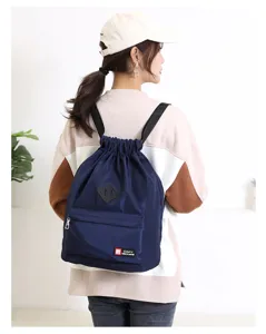 Detail view of a navy blue drawstring backpack with front zippered pocket and shoulder straps.