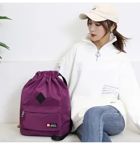 Detailed view of the purple drawstring backpack with front zipper pocket and stylish badge.