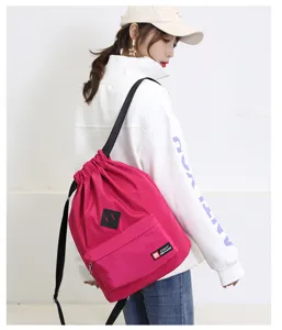 Detail view of a pink lightweight waterproof drawstring sports backpack with front pocket and straps.