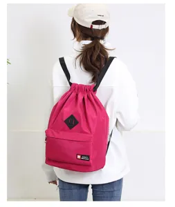 Detail view of the magenta drawstring backpack showing front pocket, diamond patch, and straps.