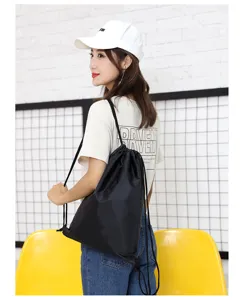 Lifestyle detail view of a black polyester drawstring backpack worn by a model for daily use.