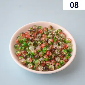 Detailed view of red and green cracked acrylic beads in a pink bowl for DIY jewelry making.