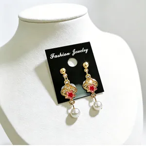 Detalle de pendientes de trébol de esmalte de estilo chino con perlas elegantes