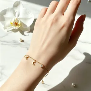Detailaufnahme eines zarten Armbands mit Goldmond und Strassstein an der Hand