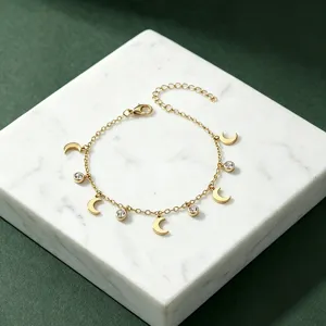 Detailansicht eines goldenen Edelstahlarmbands mit zarten Mondanhängern und Strasssteinen