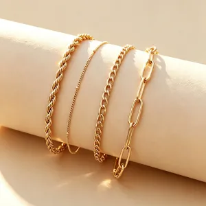 Detailopname van een vierdelige gouden roestvrijstalen armbandset met diverse kettingen