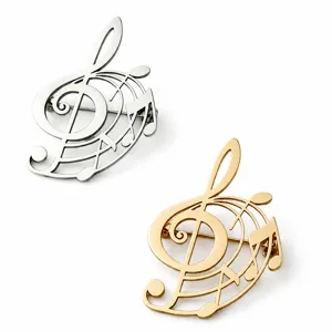 Detailed view of silver and gold stainless steel musical note brooches on white background