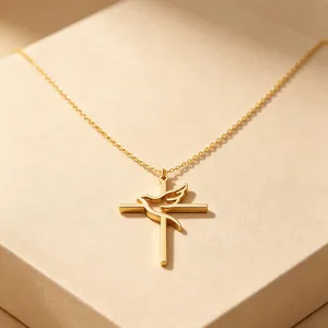 Macro view of gold hollow dove and cross pendant on minimalist stainless steel necklace