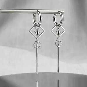 Detailopname van punk oorbellen met geometrische kegels en lange zilveren kwastjes