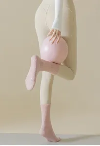 Primer plano detallado de calcetines de yoga rosados con puntos antideslizantes y textura.