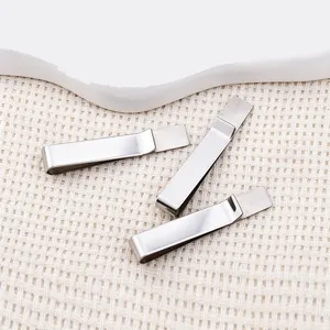 Detailed macro view of three polished stainless steel tie clips placed on a textured beige fabric