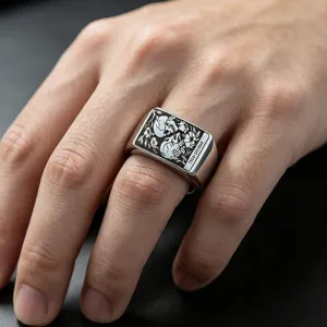Dettaglio ravvicinato di un anello a sigillo in acciaio inox con teschio e fiori incisi