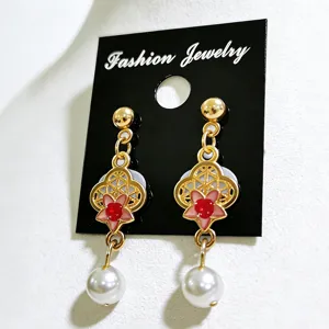 Primer plano de los detalles de flores de esmalte y perlas blancas de estos pendientes largos retro