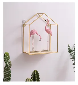 Decorative gold house-shaped wall shelf featuring pink flamingo figurines on wood.