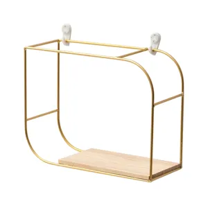 Minimalist gold metal wall shelf featuring a wooden base and white mounting hooks