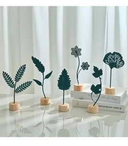 Close-up of elegant Nordic iron leaf ornaments featuring natural wood bases and soft sunlight.