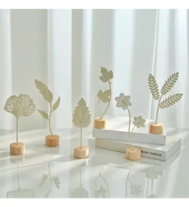 Macro view of Nordic style cream metal leaf ornaments featuring round natural wooden bases