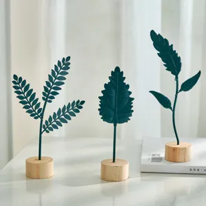 Set of three Nordic style dark green iron leaf ornaments with natural wooden bases