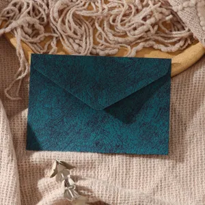 Close-up detail of a dark green textured envelope on knitted fabric background, retro style.