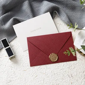 Set biglietto auguri e busta rossa con sigillo in cera, carta testurizzata per feste.