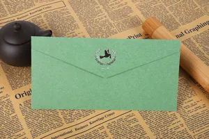 Gros plan détaillé d'une enveloppe en papier spécial vert avec marquage à chaud argenté.