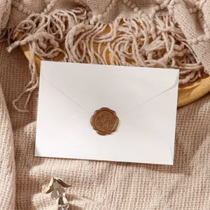 Close-up detail of white envelope with brown wax seal stamp on textured knit fabric backdrop.