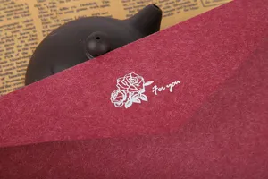 Détail d'une enveloppe en papier texturé rouge avec motif de rose pour lettres et cartes élégantes.