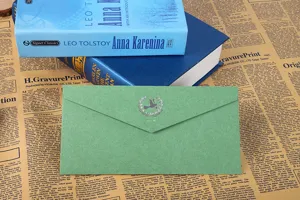 Enveloppe en papier spécial vert avec logo d'oiseau estampé à chaud argenté, détail de papeterie.