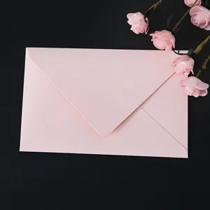 Pink paper envelope with artificial rose decor, minimalist romantic stationery for letters.