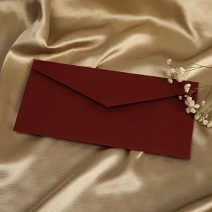 Nahaufnahme Detail eines dunkelroten strukturierten Leinenumschlags auf goldener Seide mit Blumen.