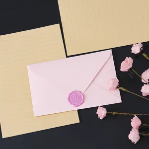 Delicate pink envelope and kraft letter paper detail shot, elegant wax seal stationery set.