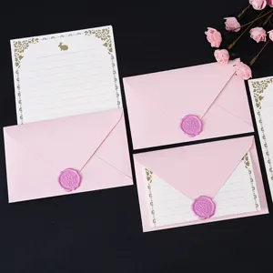 Detailed view of pink envelopes with purple wax seals and gold-bordered letter paper.