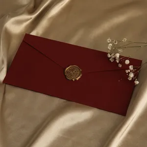 Nahaufnahme eines roten strukturierten Umschlags mit goldenem Wachssiegel und zarten Blumen.