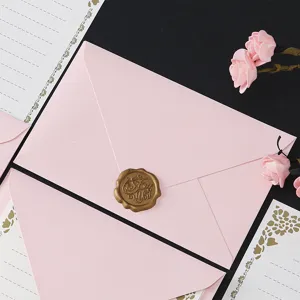 Pink envelope and stationery set detail view featuring gold wax seal stamp and floral border.