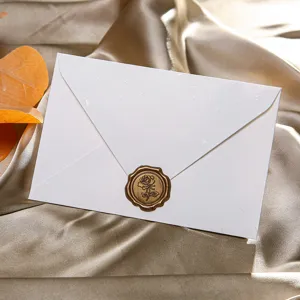 Gros plan élégant d'une enveloppe blanche avec un sceau de cire rose dorée pour lettres d'amour.
