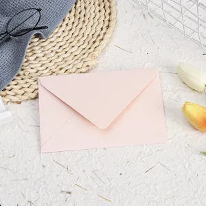 Detailed shot of a pink pearlescent envelope styled with elegant decorative props.